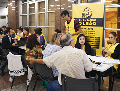Imagem com várias pessoas no projeto Amansando o Leão, onde a FAE ajuda as pessoas a fazerem suas declarações do imposto de renda